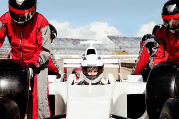 Focused driver gearing up for the race with pit crew readying the car. 