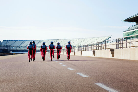 A team of pit crew walking confidently at a race track. 