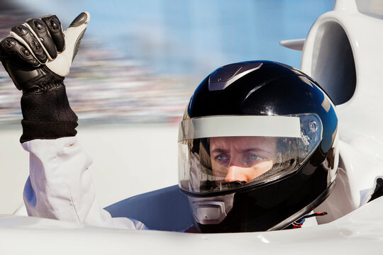 Race car driver in helmet giving a thumbsup 