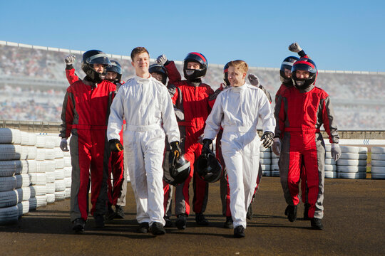 A group of kart racers in full gear celebrates on the track. 