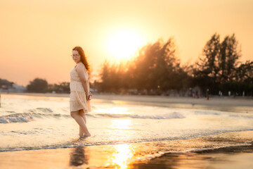 Asian woman in summer dress walks on a tropical beach the beach at Chao Samran Beach Phetchaburi Thailand, summer holiday trip Holiday travel concept.