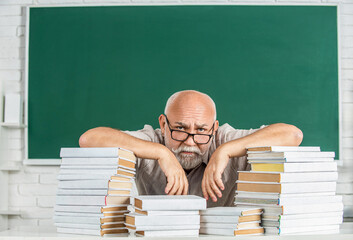 Teacher with too many books to read before exam. Teacher with books in school. Man school teacher...