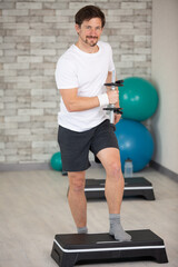 man doing step up jumps in health club