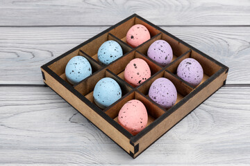 Colorful Easter eggs in a box on the wooden background