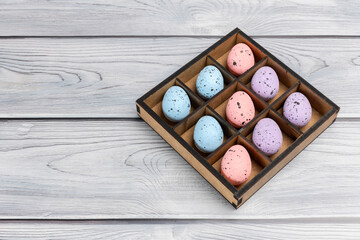 Colorful Easter eggs in a box on the wooden background