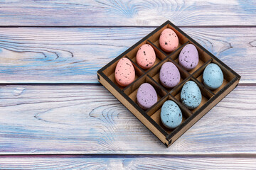 Colorful Easter eggs in a box on the wooden background