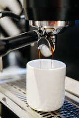 Pouring coffee stream from machine in cup. Cafe making hot Espresso. Using filter holder. Flowing fresh ground coffee. Drinking roasted black coffee in the morning