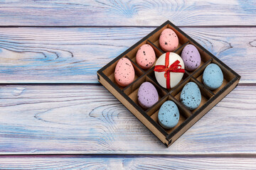 Colorful Easter eggs in a box on the wooden background