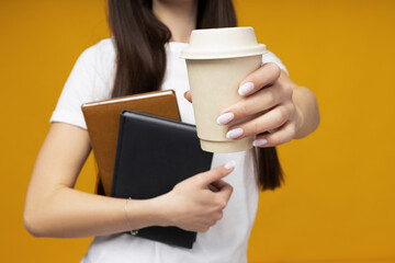 Attractive young woman with coffee and books in hands