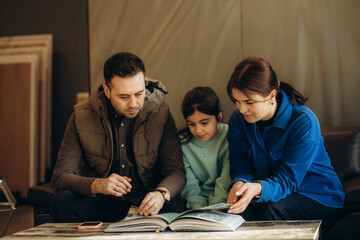 A young family is looking at a product catalog in a hardware store
