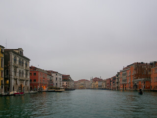 Facades of weathered buildings with windows on street of Venice city near canal water in daylight