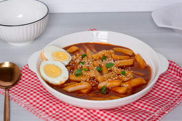 topokki or tteokbokki with two boiled eggs on a white plate and on a white background. perfect for recipes, articles, catalogues, commercials or any cooking content.