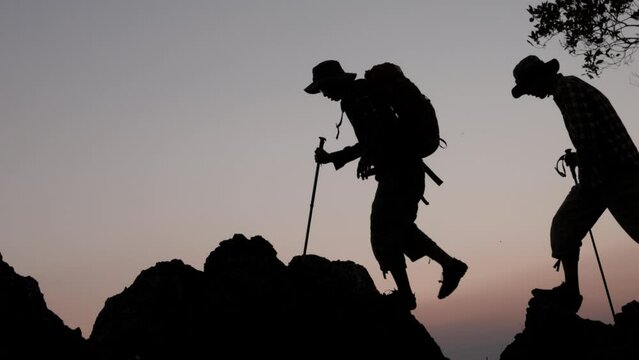 silhouette of  The hikers walking in the mountain on the sunrise background. climbing team success on the mountain. Leadership Concept, teamwork. slow motion.