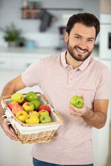 man in his kitchen holding a basket of apples