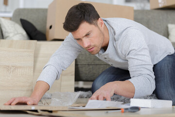 man following instructions to build furniture - obrazy, fototapety, plakaty