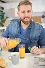 man pouring orange juice at breakfast