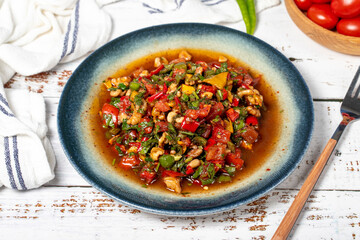 Salad with vegetables and walnuts. Traditional Asian flavors. Gavurdagi salad on white wood background