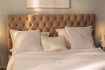 Comfortable cozy bedroom with morning light. Beige king size bed with white pillows, duvet and duvet case