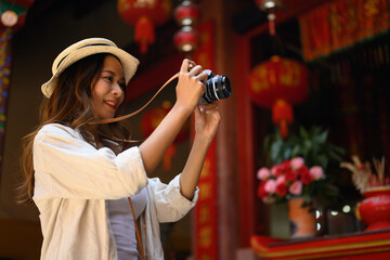 Attractive female tourist taking photo with her camera at Chinatown district in Chiang Mai, Thailand