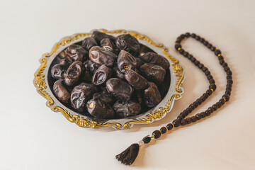Arabian tray with dates and wooden rosary. Islamic holidays concept.