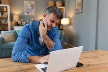 Businessman feeling pain in neck after sitting at the table with laptop. Tired man suffering of...