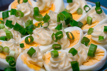 Zbliżenie na jajka ugotowane na twardo i przekrojone na pół, przybrane majonezem i szczypiorkiem
