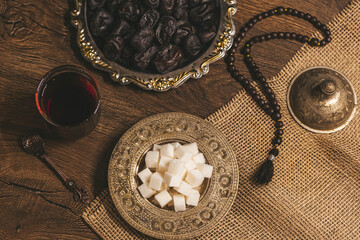 Glass of tea with sugar and dried dates on a wooden background with burlap. Ramadan Kareem holiday background. Halal meal set for fasting is obligatory for Muslim on wooden. . Soft focus. Shallow DOF.