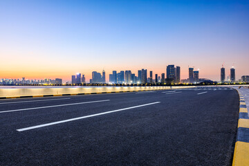Asphalt highway road and city skyline with modern buildings at sunrise