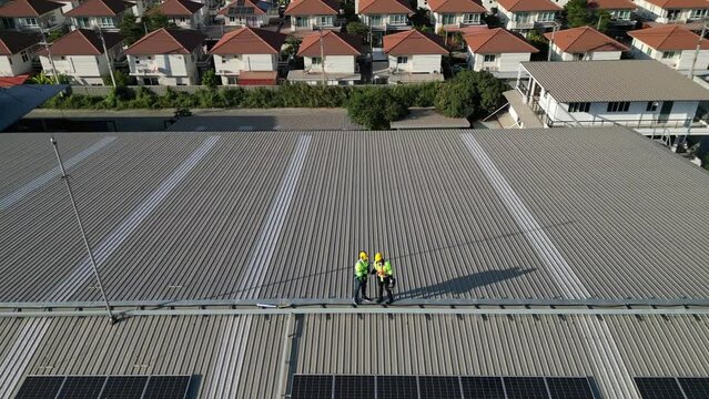 Top aerial view of engineer men inspects construction of solar cell panel or photovoltaic cell by electronic device. Industrial Renewable energy of green power. factory worker working on tower roof.