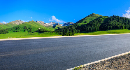 Asphalt highway road and green forest with mountain nature landscape under blue sky