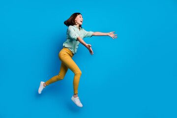 Fototapeta na wymiar Full length photo of overjoyed woman dressed teal shirt yellow trousers run to empty space catch object isolated on blue color background