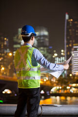 Asian engineer at work on a building site at night.