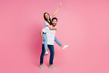 Full length photo of lovely young couple hold piggyback raise hand have fun wear trendy white outfit isolated on pink color background