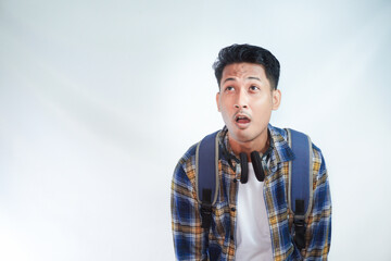 Excited young Asian man student in casual clothes backpack glasses looking aside on workspace area mockup isolated on white background. Education in high school university college concept