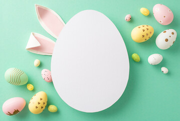 Easter creativity display: top view of colorful eggs, and attractive rabbit ears against a turquoise background, leaving an egg-shaped blank for texts or adverts