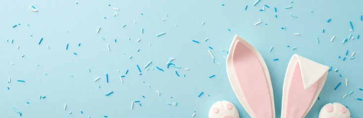 Captivating Easter display with top view of adorable bunny ears and tiny paws peeking through a sprinkle of confetti on a pastel blue backdrop, designed for inviting seasonal messages or marketing - obrazy, fototapety, plakaty