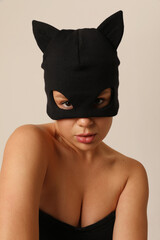 Stunning young woman wearing black cat mask posing on white background. Vertical