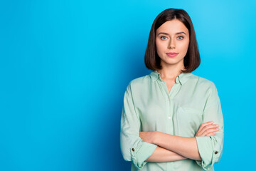 Photo of serious pretty woman with bob hairstyle dressed teal shirt keep arms folded near empty...