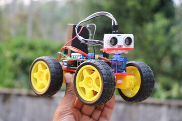 Obstacle avoiding car held in the hand. Robotic car equipped with ultrasonic sensor to sense any...