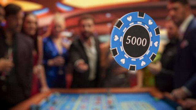 Elegantly Dressed Men and Women Enjoying Luxurious Atmosphere in a Casino. Cinematic VFX Footage with a Young Man Tossing a Casino Chip In Front of a Camera. Slow Motion Video with a Speed Ramp Effect
