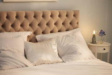 Comfortable cozy bedroom bed with beige headboard, beautiful morning light. Beige king size bed with white pillows, duvet and duvet case