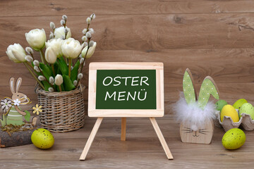 Ein Strauß Tulpen mit Ostereiern und dem Text Ostermenü auf einer Tafel.