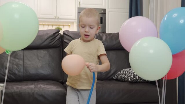3-year-old child little boy using a pump to inflate colorful balloons. Birthday party preparations at home.