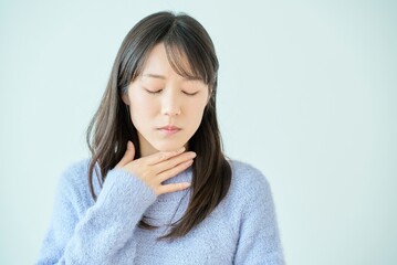 喉に違和感を感じている若い女性