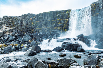 Scenic waterfall and stony hill at Thingvellir National Park, Iceland
