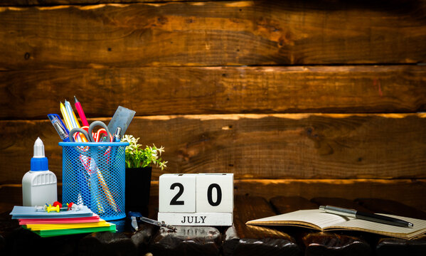 July calendar with number  20. Office background with pencils pens and ruler copy space. Beautiful background planner calendar on a brown wooden background, space for text.