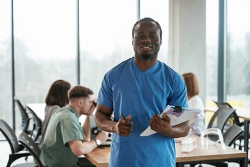 Obraz premium Black man is standing in front of colleagues. Group of doctors are together indoors