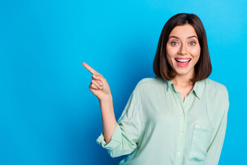 Naklejka premium Photo of positive woman with bob hairstyle dressed turquoise shirt indicating at discount empty space isolated on blue color background