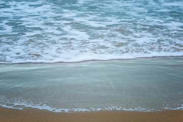 Foam wave on the sandy shore. Relaxation at the resort and activity in nature. Background. Space for text.