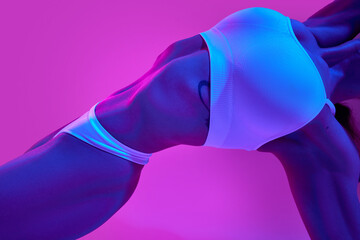 Slim female body, belly and breast. Model posing white underwear. in blue neon light against...